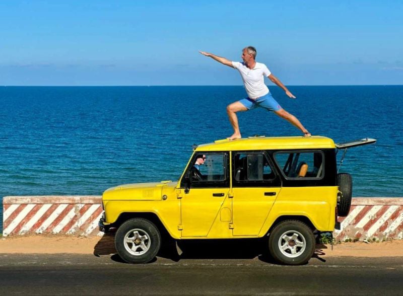 Jürgen Zenger steht auf seinem Auto direkt am Meer.