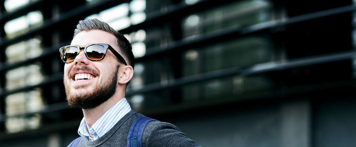 Allianz Pension Partners - Ausgelernte: Ein Mann steht vor einem Gebäude und lächelt