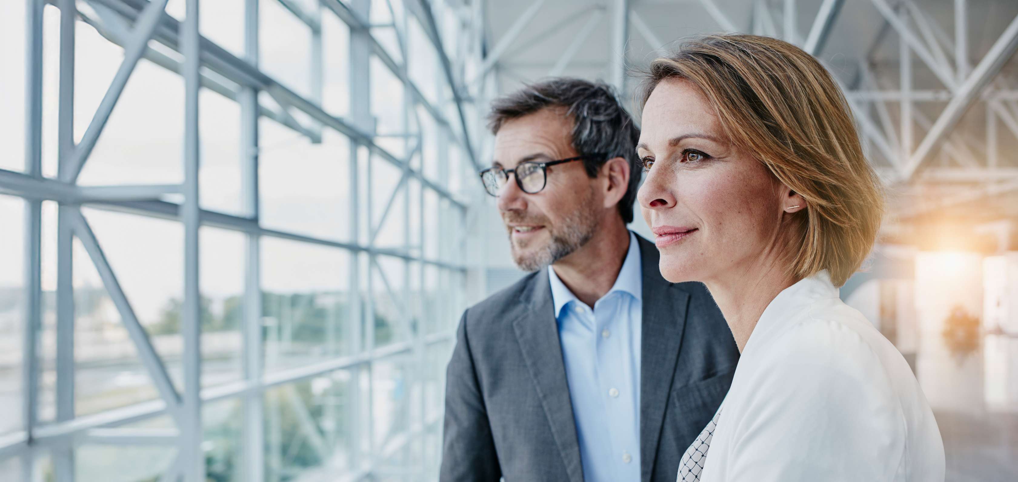 Allianz Pension Partners: Leistungen und Produkte. Zwei Personen stehen am Fenster und blicken nach draußen.