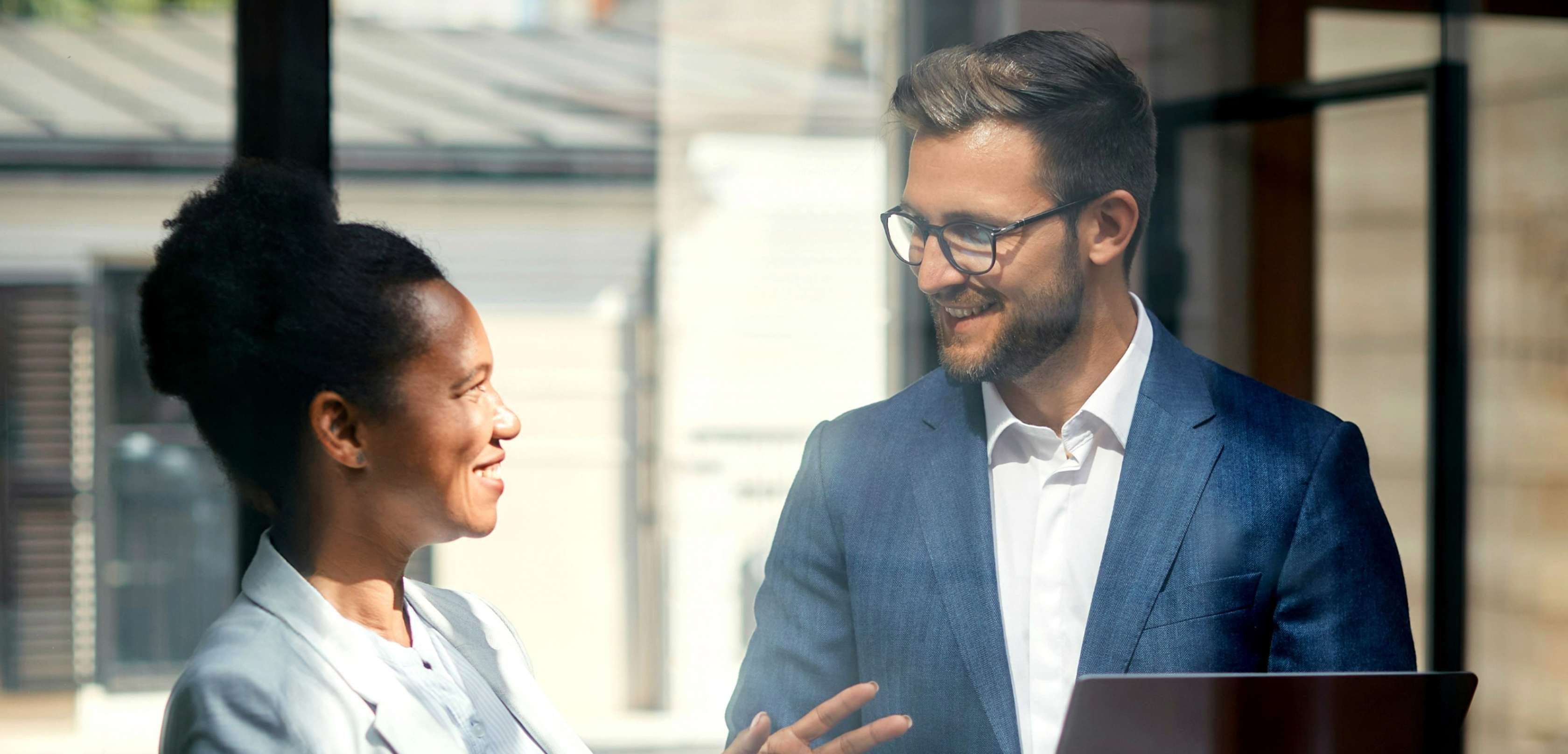 Allianz Pension Partners: betriebliche Zukunftsvorsorge. Ein Mann und eine Frau besprechen sich und lächeln sich an.