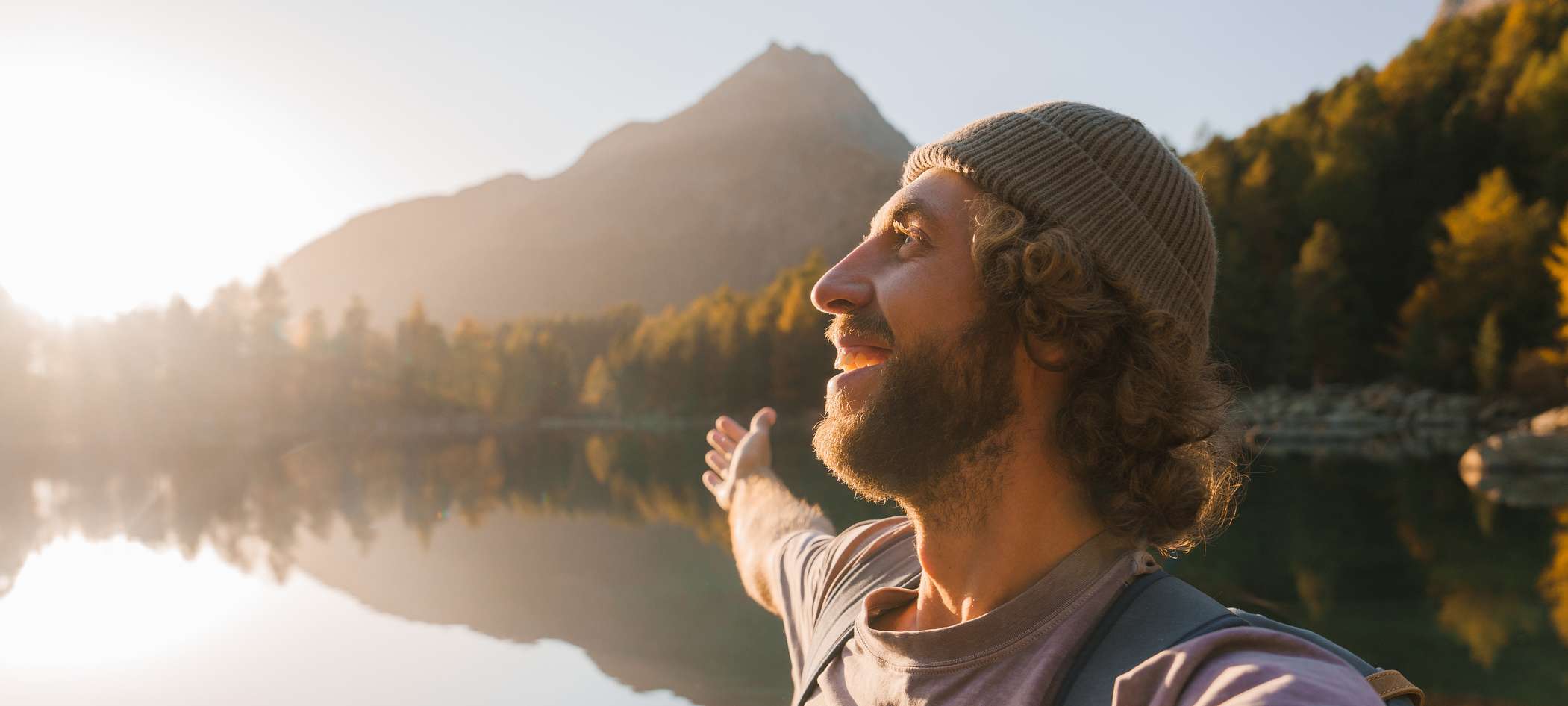 Allianz Pension Partners: Zeitkonten. Ein Mann steht am See und genießt die Sonne.